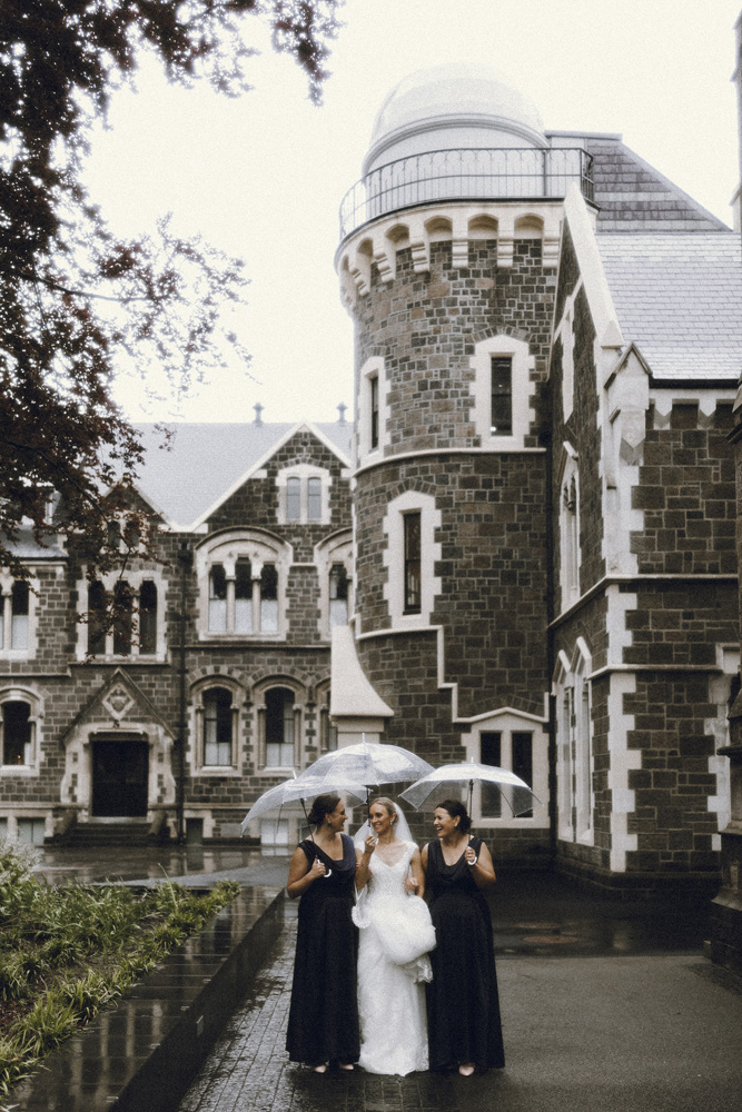 Destination, European-feel portraits of the bridal party walking through The Great Hall with their umbrellas. Film portrait captured by Eilish Burt Photography