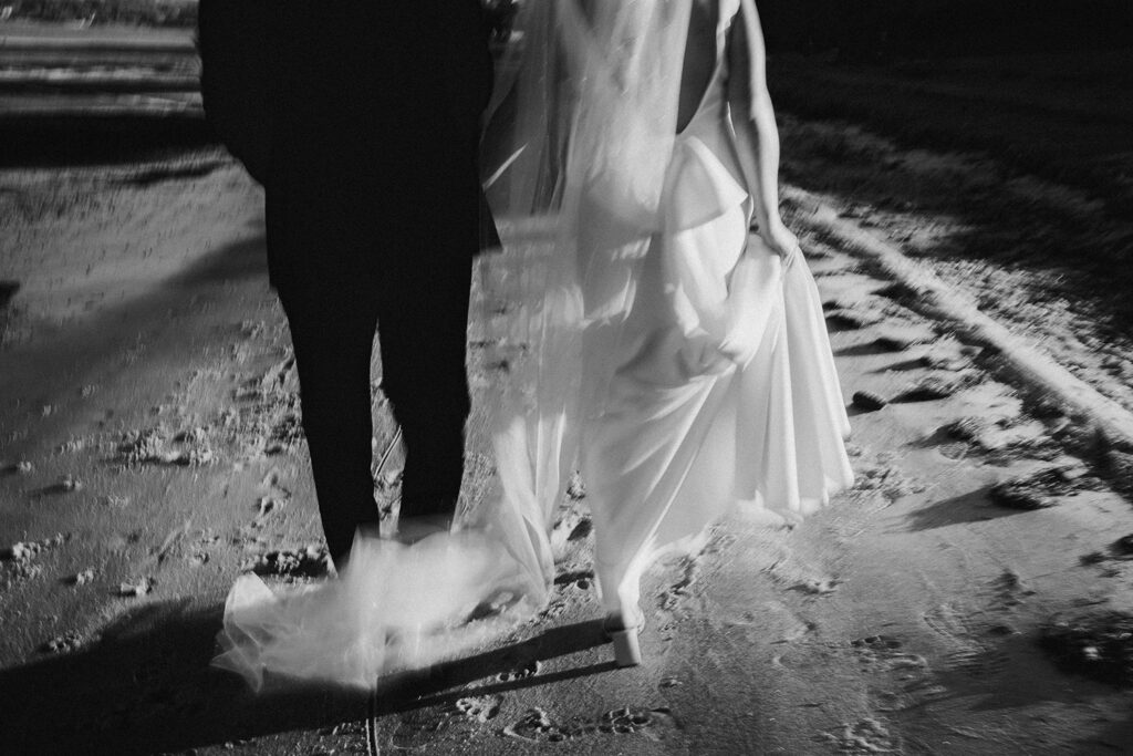 Film photograph of a bride and groom walking along the beach in Tauranga