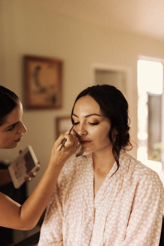 Makeup Artist Prita Fermah puts the finishing touches on the bride for her wedding day in Whakatane. Captured by Eilish Burt Photography