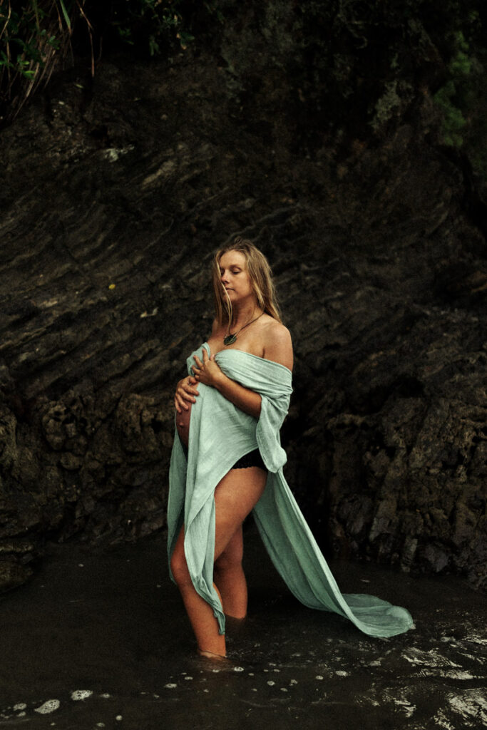 A pregnant mum having her maternity photoshoot in the water at Ohope Beach by Eilish Burt Photography