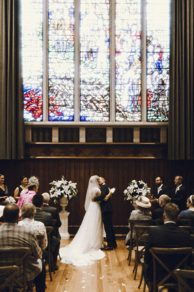 Wedding couple share their first kiss as husband and wife in The Great Hall, Christchurch. Captured by Eilish Burt Photography