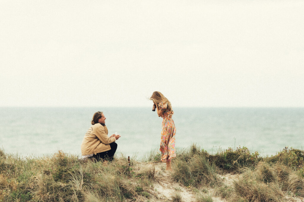 The first moment of a surprise proposal of a couple becoming engaged on the beach of Papamoa by Eilish Burt Photography
