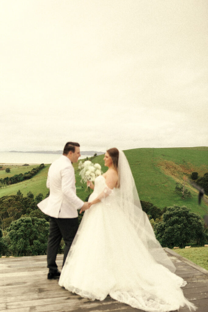 A wedding portrait captured by Eilish Burt Photography of a couple at Kauri Bay Boomrock, Auckland standing in front of the amazing NZ country landscape