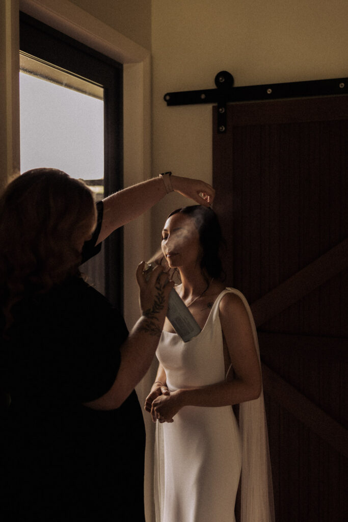 A portrait of Lissy Steens applying hair product to her wedding client on her wedding day. Captured by Eilish Burt Photography