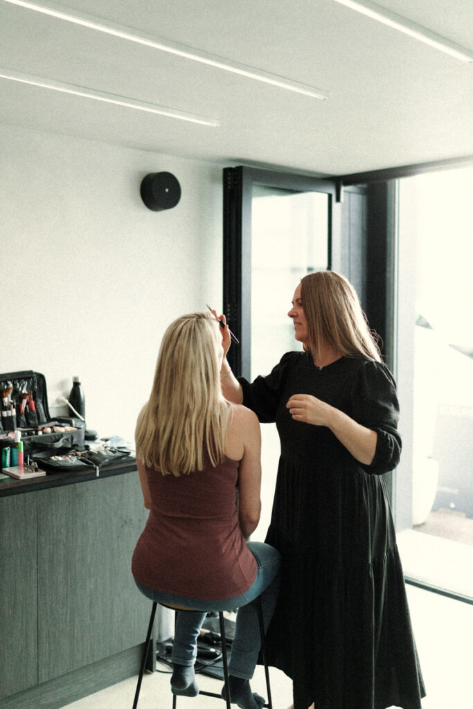 Hair and makeup artist Desiree applying wedding glam to her client in Tauranga