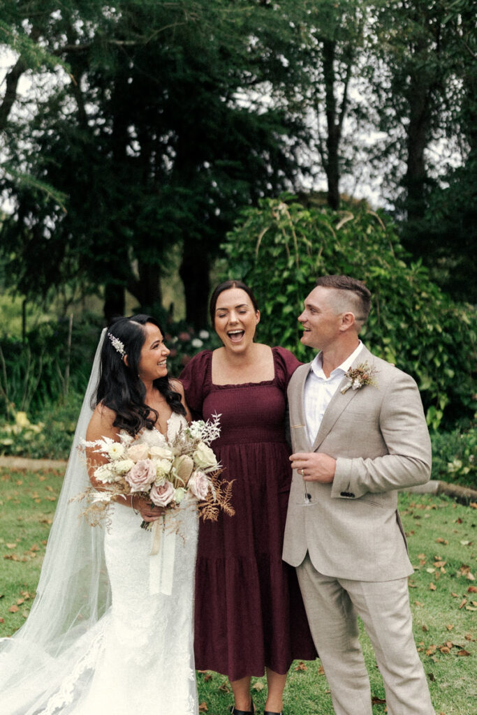 A joyful portrait of wedding celebrant Geo standing with her couple from their wedding in Whakatane. Captured by Eilish Burt Photography