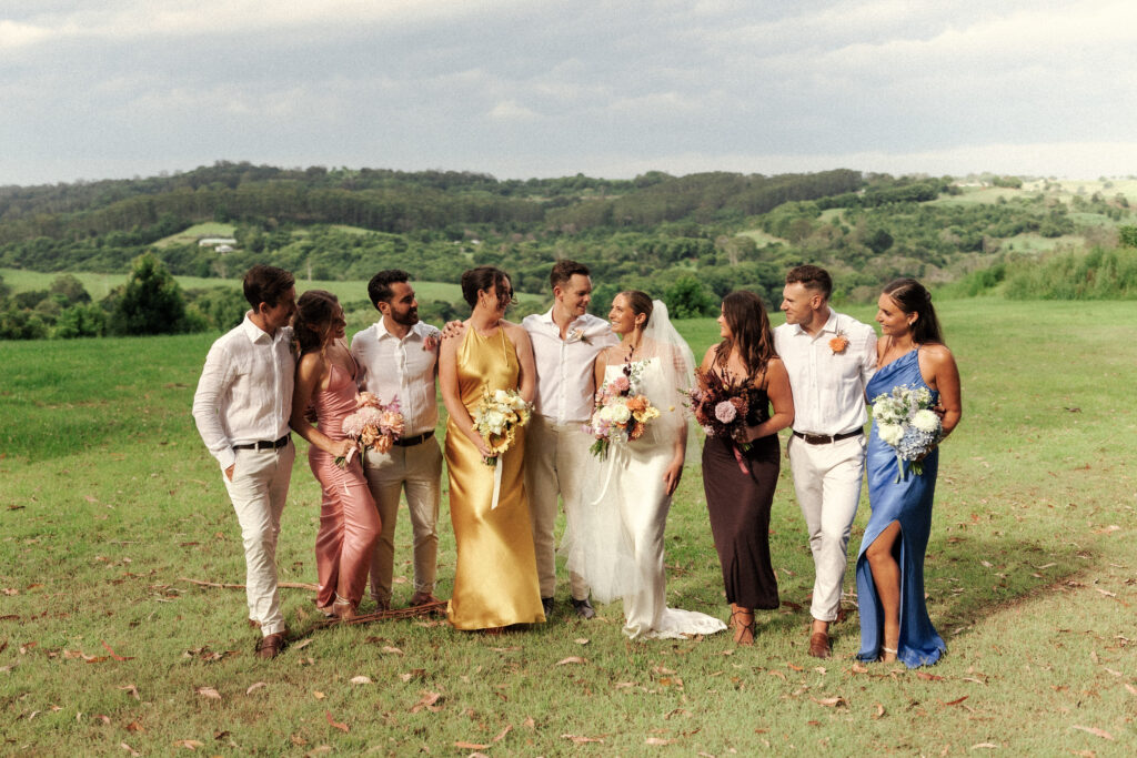 A fun bridal party portrait of good friends dressed in vintage colours at the grooms family farm in Byron Bay, Australia