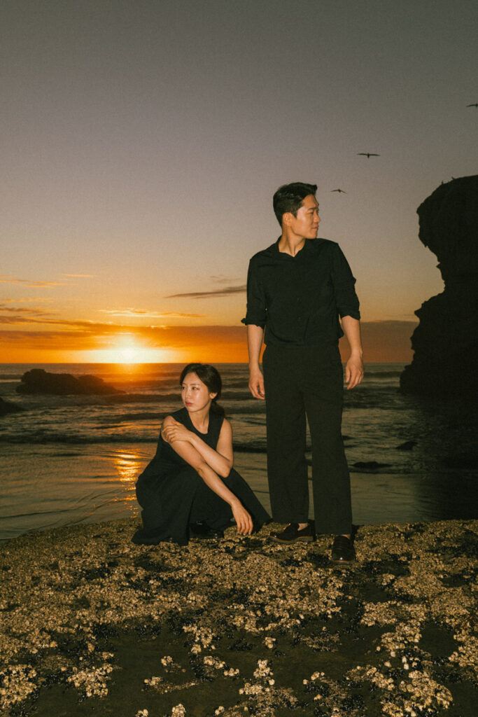 A film photograph of an engaged couple on the cliffs of Muriwai Beach in Auckland