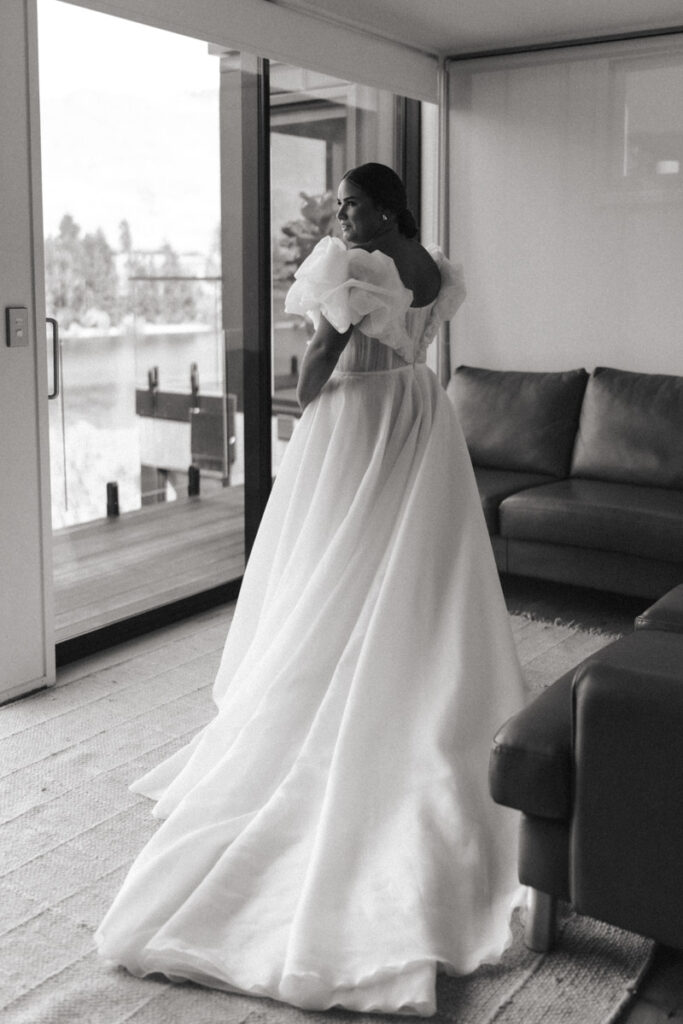 A bride standing in her wedding dress about to go to her ceremony in Queenstown. Black and white portrait captured by Eilish Burt Photography