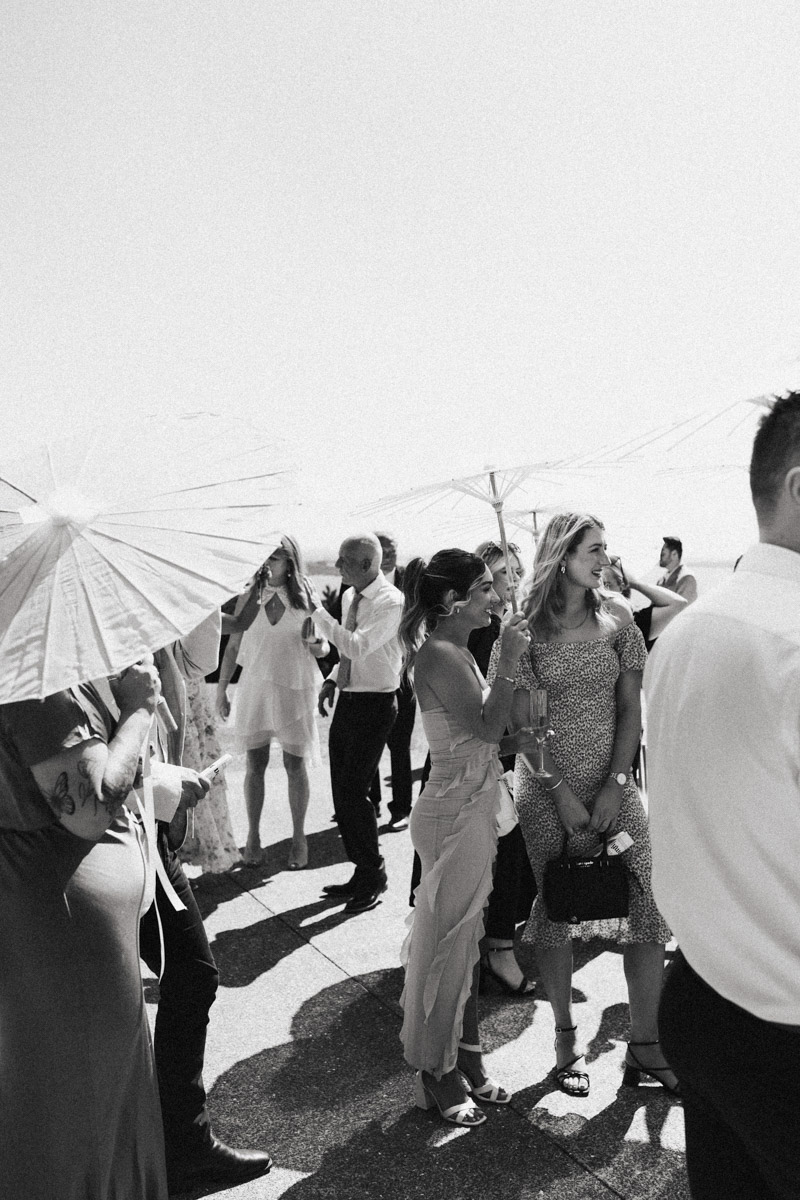 Wedding guests look for shade at a Mudbrick, Waiheke Wedding. Captured by Eilish Burt