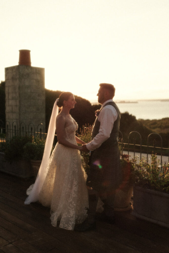 The bride and groom have a sunset photo on top of the Mudbrick venue on Waiheke Island. Captured by Eilish Burt Photography.