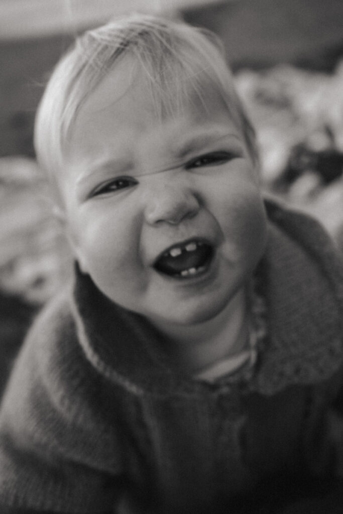 Baby Ruby shows off her teeth in her family portrait at Ohope. Captured by Eilish Burt Photography.