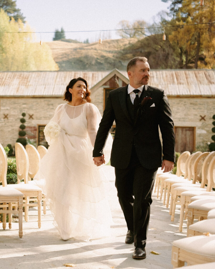 A wedding portrait of a bride and groom walking up the aisle at their Ayrburn Wedding in Queenstown.