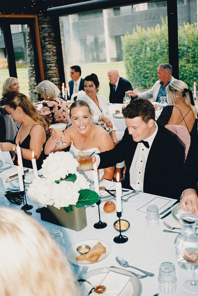 The bride and groom have big smiles on their faces at the reception table at the Edgewater Estate in Wanaka.